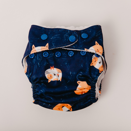 Eco-friendly cloth diaper with a fox print on navy blue fabric. adjustable snaps for a perfect fit and soft, breathable material that’s gentle on baby skin. Reusable and washable, designed for day & night use. parents seeking sustainable diapers.